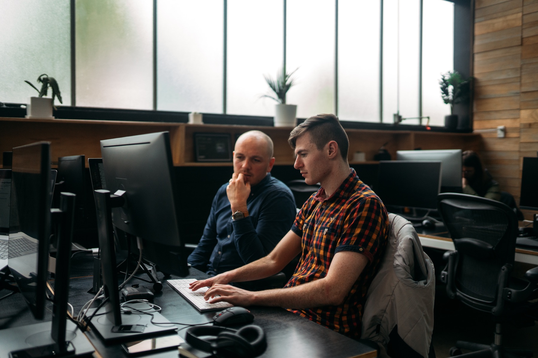 Two people at a desk, looking at a screen and having a discussion